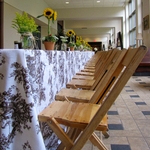 Country Picnic themed table display with wooden chairs, floral linens, potted sunflowers and garden florals